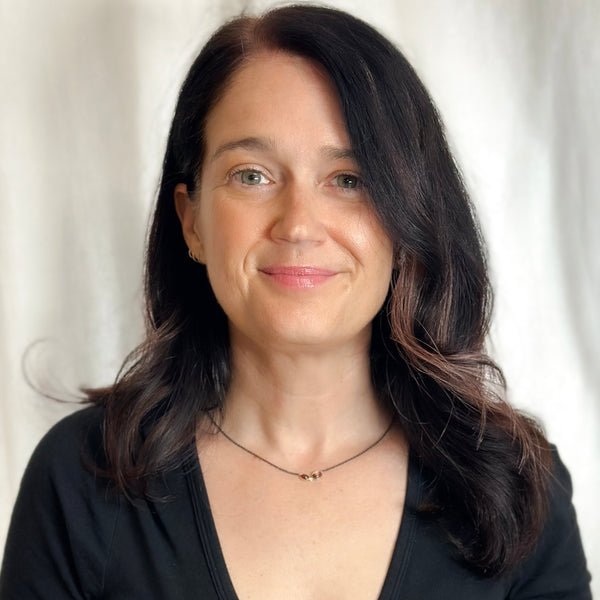 Necklace with two oval Umba sapphires and a small diamond between them, set in recycled 18k yellow gold on an oxidized silver cable chain. Shown on a model.