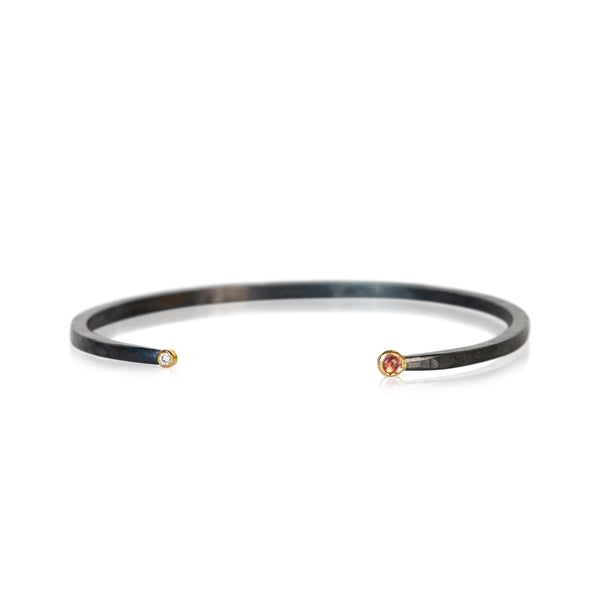 Oxidized sterling silver cuff bracelet with a diamond on one end and a small round pink tourmaline cabochon on the other, both set in 18k yellow gold.
