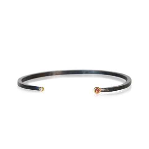 Oxidized sterling silver cuff bracelet with a diamond on one end and a small round pink tourmaline cabochon on the other, both set in 18k yellow gold.