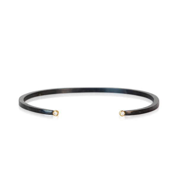 Alt Text
Oxidized sterling silver cuff bracelet with a diamond set in 18k yellow gold at each end.