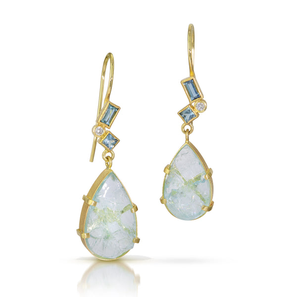 Photo of karin jacobson jewelry design pear shaped aquamarine and diamond earrings in 18k yellow gold. The pear shaped rough aquamarines are set in a hand fabricated 18k yellow gold setting with a cluster of faceted aquamarines and post consumer recycled diamonds on the bail. These earrings have french wires.
