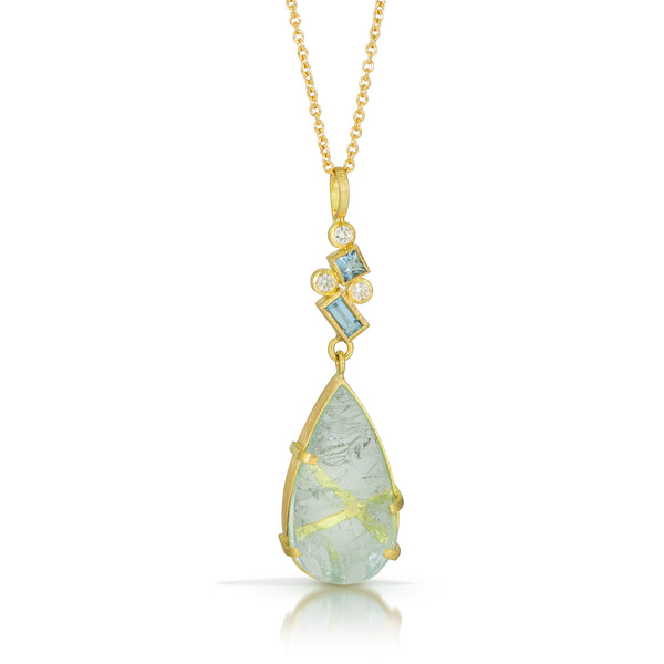 Photo of karin jacobson jewelry design pear shaped aquamarine and diamond necklace 18k yellow gold. The pear shaped rough aquamarine is in a hand fabricated 18k yellow gold setting with a cluster of faceted square and baguette aquamarines & round diamonds on the bail. Shown hanging on an 18k yellow gold cable chain.