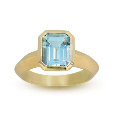 emerald cut aquamarine in fairmined 18k yellow gold on a white background