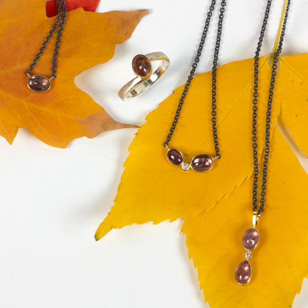 Collection of Umba sapphire jewelry in recycled 18k yellow gold on an oxidized silver cable chains. Shown on autumn leaves.