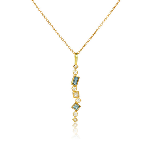Shows an 18k yellow gold confetti necklace with various square, rectangle and round aquamarines and diamonds, hanging from a gold cable chain on a white background. Close up photo.