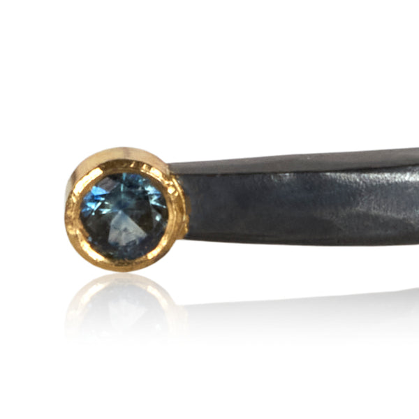 close crop of blue sapphire in 18k gold on oxidized sterling bracelet