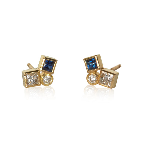Shows a pair of dark blue sapphire and diamond studs on white. Each stud has one square diamond, one square blue sapphire and one round diamond.