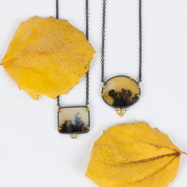 Round dendritic agate pendant in oxidized sterling silver with 18k yellow gold prongs and a cluster of three small diamonds below, shown on an oxidized silver cable chain. Shown with 2nd pendant and yellow leaves.