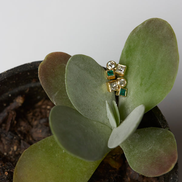 Photo of karin jacobson jewelry design diamond & emerald confetti studs in 18k yellow gold. The diamonds and emeralds are both post-consumer recycled - this time propped on a plant.