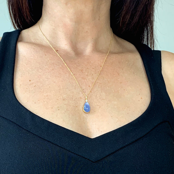 Photo of karin jacobson jewelry design pear shaped chalcedony cabochon and diamond necklace in sterling silver, 22k & 18k yellow gold. It has one diamond at the top of the pendant. Shown on a model