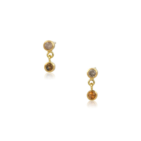 This photo shows a pair of earrings that have rosy pink sapphires in bezels on top with amber colored sapphires in bezels dangling below - shown on white background.