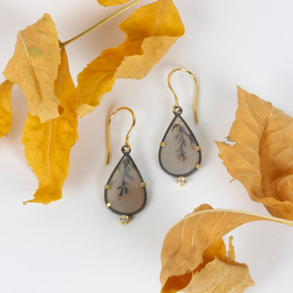 Pair of pear-shaped dendritic agate drop earrings in oxidized sterling silver with 18k yellow gold prongs, each accented with a small diamond below and finished with 18k gold French wires. Shown with yellow autum leaves.