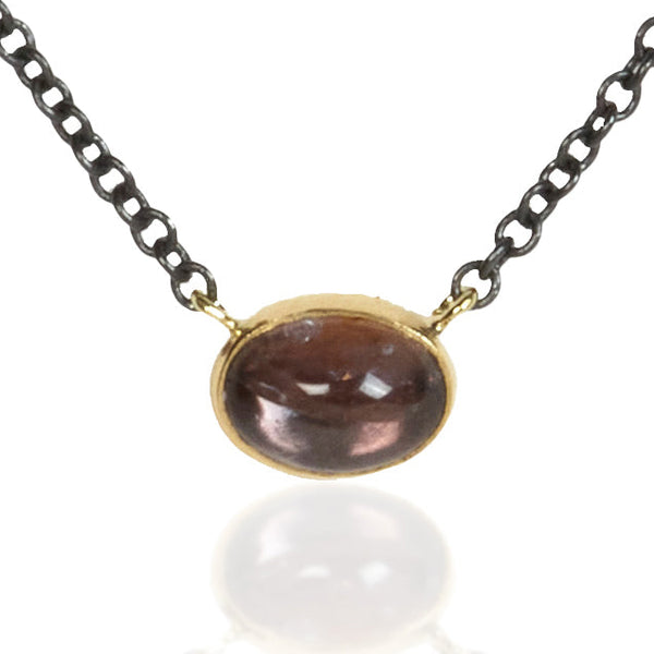 Small oval Umba sapphire pendant in recycled 18k yellow gold on an oxidized silver cable chain.