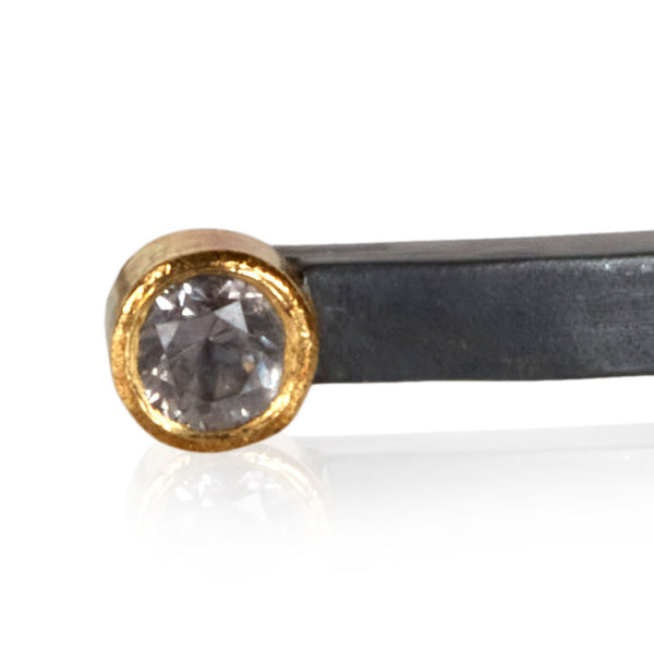 close crop of lavender/gray sapphire in 18k gold on oxidized sterling bracelet