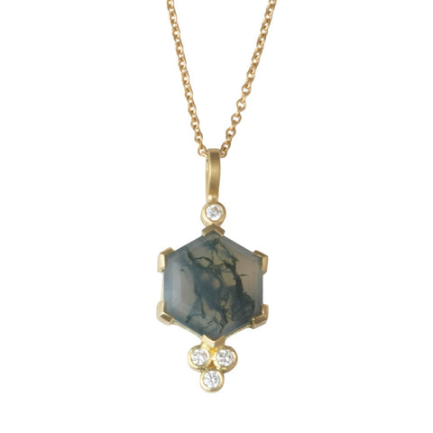 Photo of karin jacobson jewelry design hexagon shaped moss agate and diamond necklace in Fairmined™ 18k yellow gold. The pendant has a hexagon shaped moss agate which is translucent white with mossy green veins and has one diamond at the top under the bail, and a cluster of three diamonds at the bottom. Shown hanging from a gold chain.