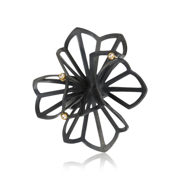 shows the top view of a large "origami" ring in oxidized sterling silver with 3 diamonds set in 18k gold. The origami looks kind of like a flower. Shown on white background.