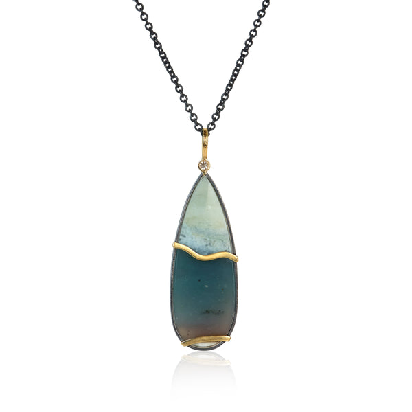 Teardrop-shaped opalized wood pendant necklace with one diamond at the top on a white background. The opalized wood has some brown at the bottom, blue-green in the middle and white at the top. This photo shows the back of the pendant.