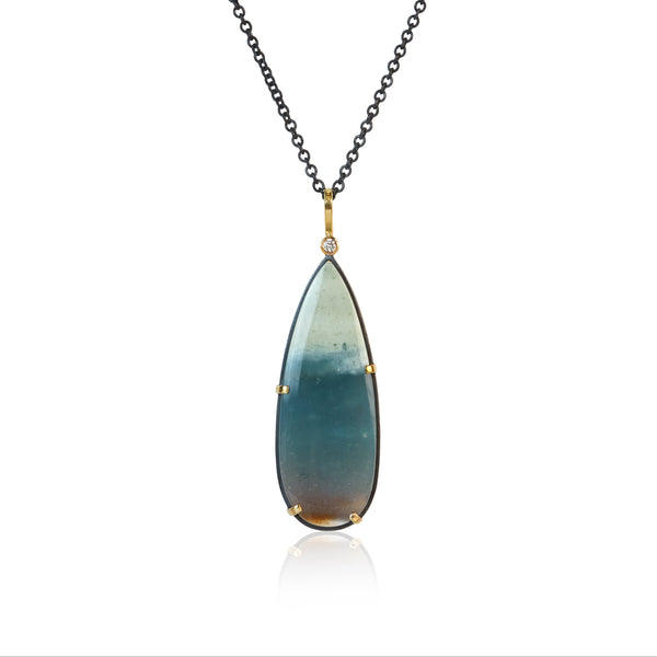 Teardrop-shaped opalized wood pendant necklace with one diamond at the top on a white background. The opalized wood has some brown at the bottom, blue-green in the middle and white at the top.