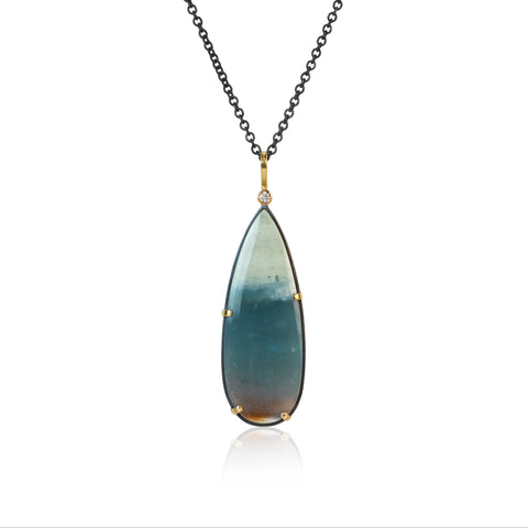 Teardrop-shaped opalized wood pendant necklace with one diamond at the top on a white background. The opalized wood has some brown at the bottom, blue-green in the middle and white at the top.