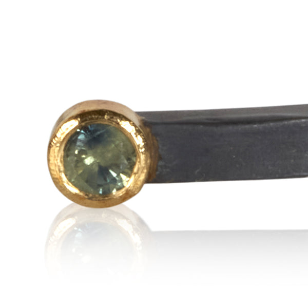 close crop of bi-color sapphire in 18k gold on oxidized sterling bracelet