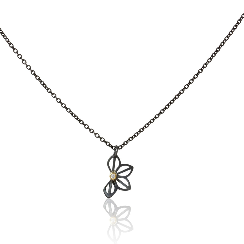 Karin Jacobson Jewelry's petite anise fold necklace with tiny diamond - it shows an oxidized sterling silver flower-like pendant with a 2mm diamond set in 18k gold, on an oxidized sterling chain. photographed on white.