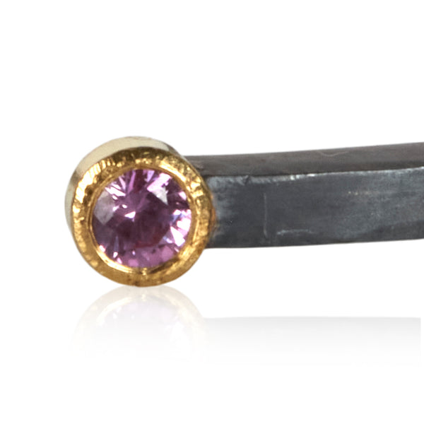 close crop of bright pink sapphire in 18k gold on oxidized sterling bracelet