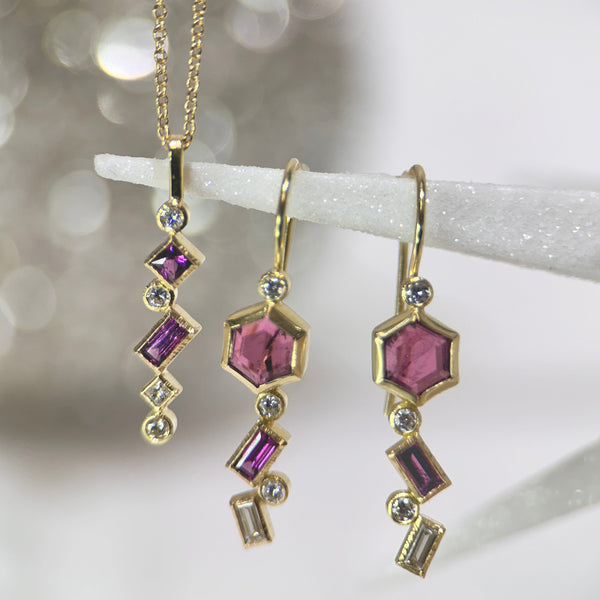 This photo shows pink tourmaline, garnet and diamond dangle earrings with grape garnet and diamond confetti necklace on a sparkly gray background.