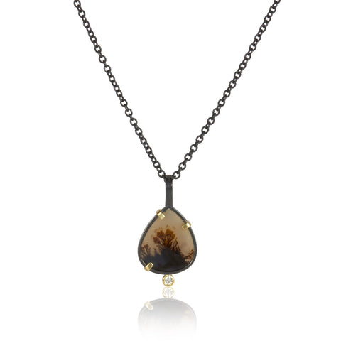 Small pear-shaped dendritic agate pendant in oxidized sterling silver with 18k yellow gold prongs and a single diamond accent below, shown on an oxidized silver cable chain.