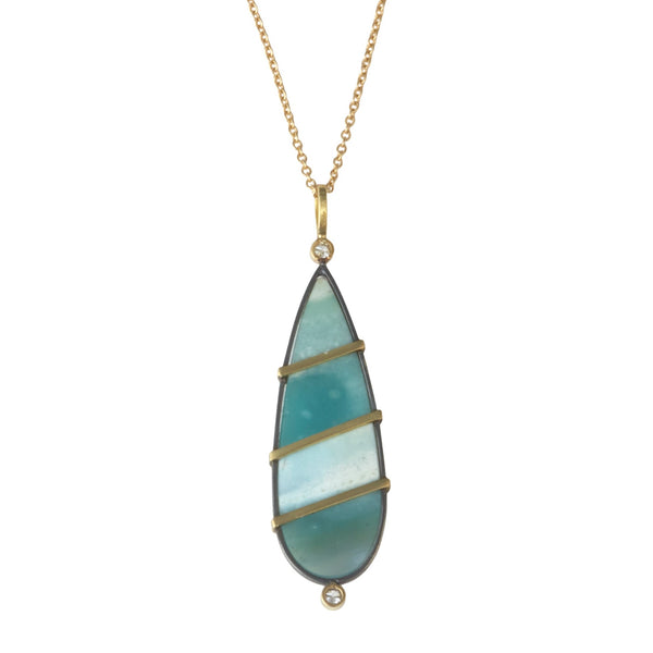 Photo of karin jacobson jewelry design opalized wood and diamond necklace in sterling silver and 18k yellow gold with 2 diamonds, shown hanging from a gold chain. the gem is pear shaped with teal and white stripes. back side shown.
