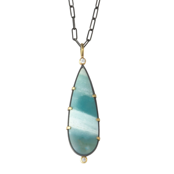 Photo of karin jacobson jewelry design opalized wood and diamond necklace in sterling silver and 18k yellow gold with 2 diamonds, shown hanging from an oxidized silver chain. the gem is pear shaped with teal and white stripes. front side shown.