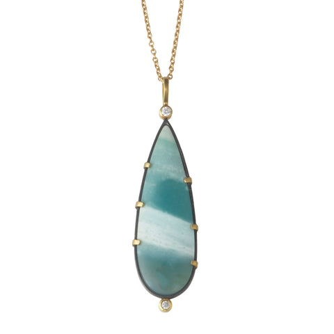 Photo of karin jacobson jewelry design opalized wood and diamond necklace in sterling silver and 18k yellow gold with 2 diamonds, shown hanging from a gold chain. the gem is pear shaped with teal and white stripes. front side shown.