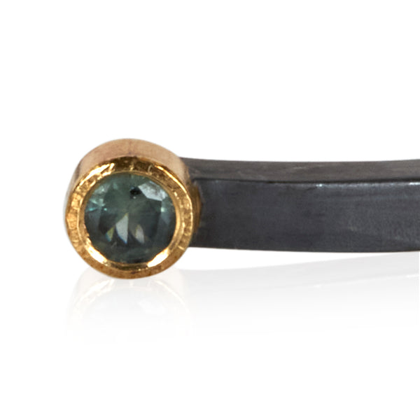 close crop of teal sapphire in 18k gold on oxidized sterling bracelet