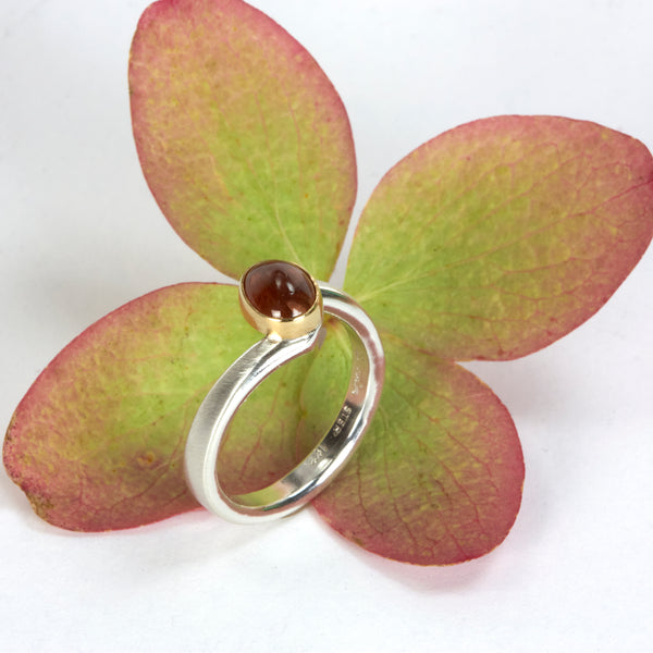 Sterling silver ring with an oval Umba sapphire bezel set in 18k yellow gold. Shown next to autumn leaves.