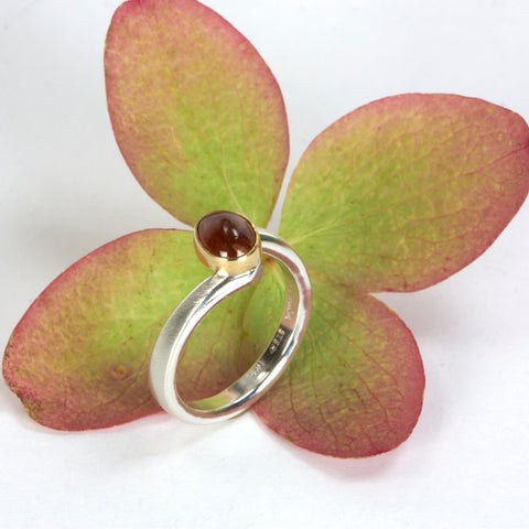 Sterling silver ring with an oval Umba sapphire bezel set in 18k yellow gold. Shown next to autumn leaves.